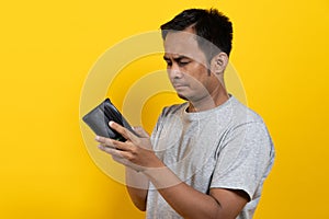 Financial bankruptcy man opening empty wallet isolated on yellow background