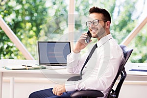 Financial businessman having a phone call while sitting at office desk and working