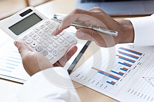 A financial businessman, a young man analyzes financial data using a computer and calculator to compute and summarize