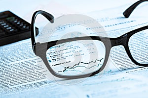 Financial chart and graph currencies see through glasses lens on financial newspaper