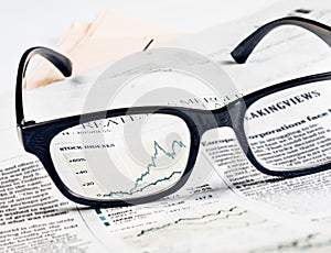Financial chart and graph of stock indexes see through glasses lens on financial newspaper