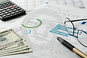 Financial charts report sheet with pen, calculator, eyeglasses, dollar banknotes