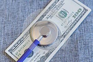 Financial checkup: Stethoscope on pile of U.S. hundred dollar bill on grey background. financial wellness