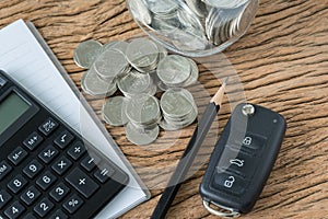 Financial concept as car key with stack of coin, pencil note boo