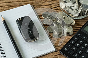 Financial concept as car key with stack of coin, pencil note boo