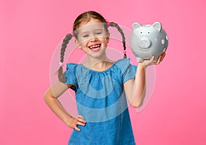 Financial concept of children`s pocket money. child girl with piggy Bank      on a colored pink background