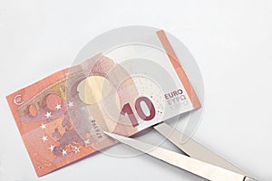 Financial concept: cut the debt. a ten euro bill, a pair of scissor and a calculator on white background with copy space