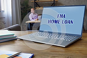 Financial concept about FHA HOME LOAN with inscription on the Compact laptop A successful businessman with documents on the