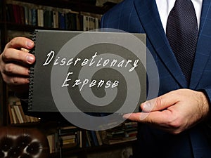Financial concept meaning Discretionary Expense with phrase on the black notepad