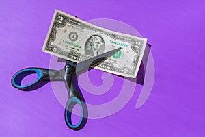 Financial concept.scissors cut money on purple background.Concept of spending money,scissors cut money of USA
