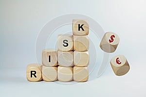 Financial concept for speculation with currencies, stacked wooden cubes with the word RISK and falling cubes with Dollar and Euro