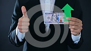 Financial consultant with dollar banknotes showing thumbs up and down, growth