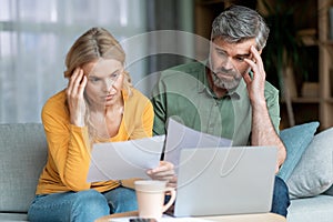 Financial Crisis. Pensive Middle Aged Couple Checking Documents At Home