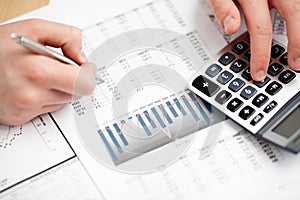 Financial data analyzing. Counting on calculator.