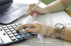 Financial data analyzing. Counting on calculator and laptop. Hand with pen on financial table