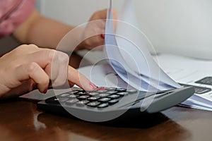 Financial data analyzing hand writing and counting on calculator at home on wooden desk