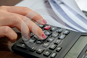 Financial data analyzing hand writing and counting on calculator at home on wooden desk
