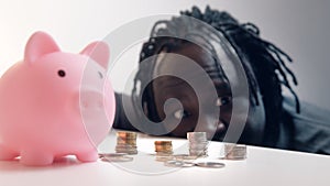 Financial decision, investments and savings. Funny man looking into the coins in front of the piggy bank. Racking focus