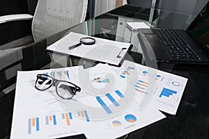 Financial documents with magnifying glass and insurance lie on black table in office close-up