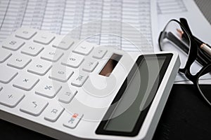 Financial documents and white calculators on black wooden desks