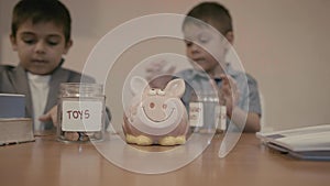 Financial education and child savings. Two boys kids sorting coins between toys jar and emergency fund with piggy bank