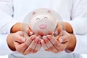 Financial education concept - adult and child hands holding piggy bank