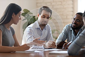 Financial expert holding brainstorming meeting with multiracial engaged colleagues.