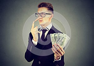 Financial fraud concept. Liar business man in suit and glasses with dollar cash