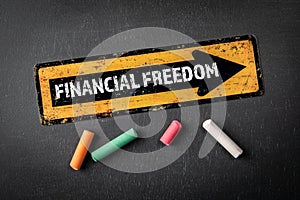 Financial Freedom. Direction arrow with text on a dark chalkboard background