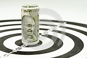 Financial goal or target concept, Indian rupee banknote roll targeted at the center of yellow dartboard photo