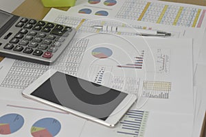 Financial graphs and charts with smartphone, eyeglasses, calculator and pen on desk