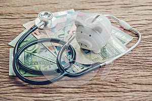 Financial health check or EU economic concept, saving white piggy bank with stethoscope on pile of Euro banknotes on wooden table