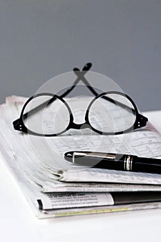 Financial newspaper break background with pen and glasses business man