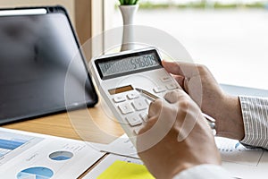 The financial officer presses the white calculator, he calculates the numerical balance on the document to verify the correctness