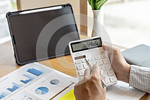 The financial officer presses the white calculator, he calculates the numerical balance on the document to verify the correctness