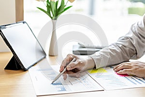 The financial officer uses a pen to point at the numbers on the financial documents to verify the correctness before submitting