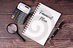 Financial plan text on notepad, pen, calculator, magnifying glass flat lay