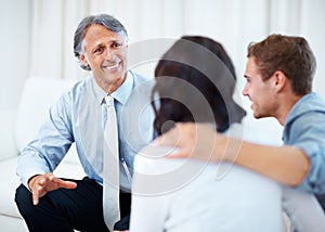 Financial planner discussing with young couple. Mature financial planner discussing with young couple at home.