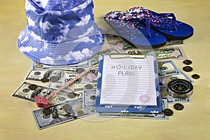 Financial plans for vacation concept. Blue sun hat, beach slippers, compass, notebook with pencil, money
