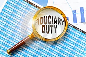 Financial reports, charts and a magnifying glass are on the table. Inside the magnifier there is an inscription - FIDUCIARY DUTY