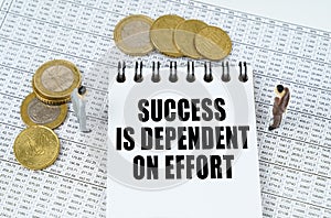 On financial reports there are figurines of people, coins and a notepad with the inscription - SUCCESS IS DEPENDENT