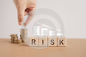 Financial risk assessment and management concept. RISK word on wooden cube blocks and white bar graph with blurred hand