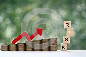 Financial risk assessment,Red arrow graph on stack of coins money and risk word on natural green background, Business investment