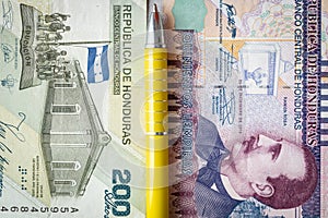 Financial settlements in Honduras, concept, 200 and 500 Lempiras banknotes stacked next to each other, yellow pen between them,