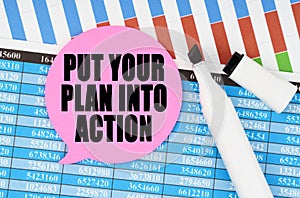 On financial statements and charts there is a marker and a sticker with the inscription - PUT YOUR PLAN INTO ACTION