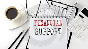 FINANCIAL SUPPORT text on the paper with calculator, notepad, coffee ,pen with graph