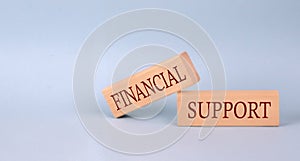 FINANCIAL SUPPORT text on the wooden block, blue background