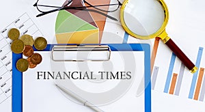 FINANCIAL TIMES Business reports, blank paper , data tables and charts,magnifier,coins - directly above view of office table