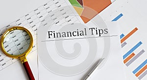 FINANCIAL TIPS Business reports, blank paper , data tables and charts,magnifier, - directly above view of office table workspace