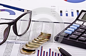 Financial tools, calculator, pen and specs over a report